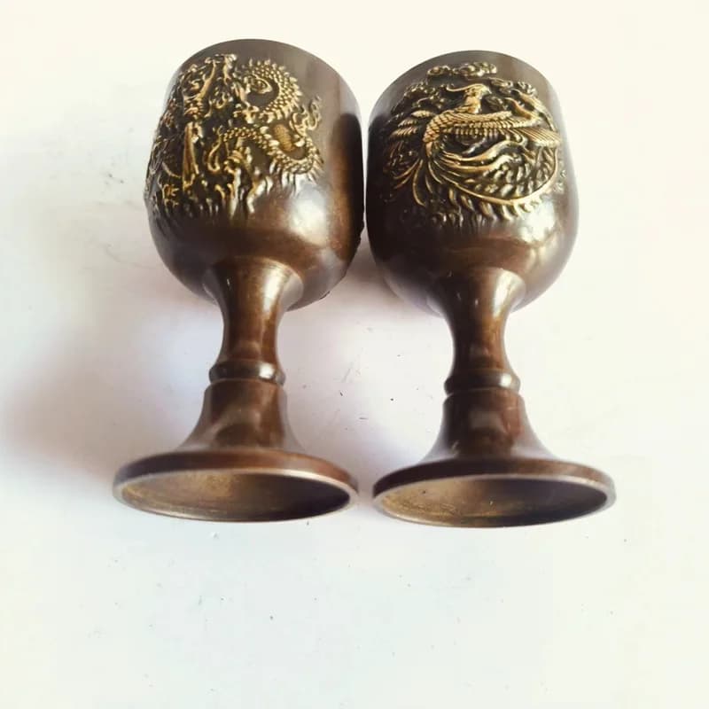 A pair of vintage brass dragon and phoenix motif , antique gilded household wine glasses, decorative items